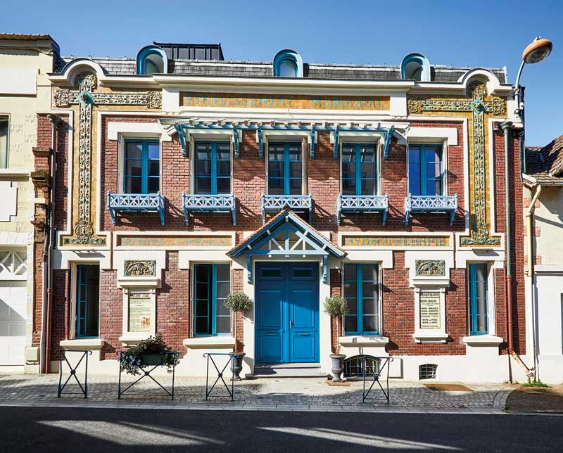 façade en brique avec une porte d'entrée et des volets bleus
